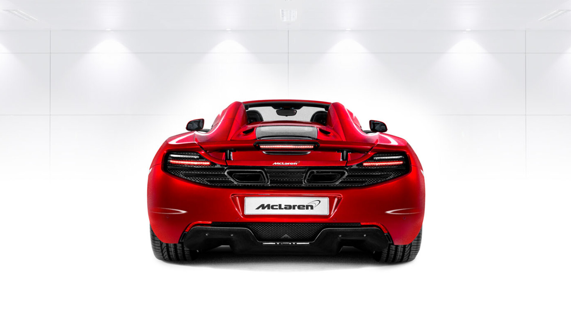 Rear view of a red McLaren 12C Spider, photographed in a bright white studio environment.