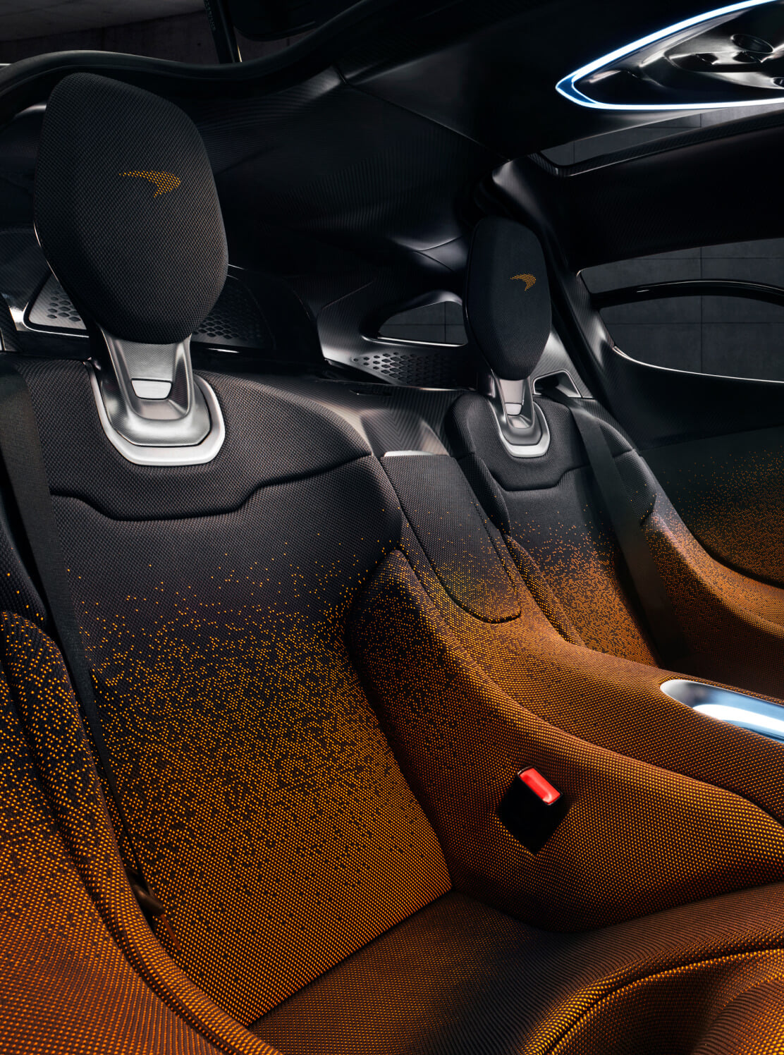 The interior of McLaren W1 with orange fading into black seats with an orange McLaren logo on the headrest.