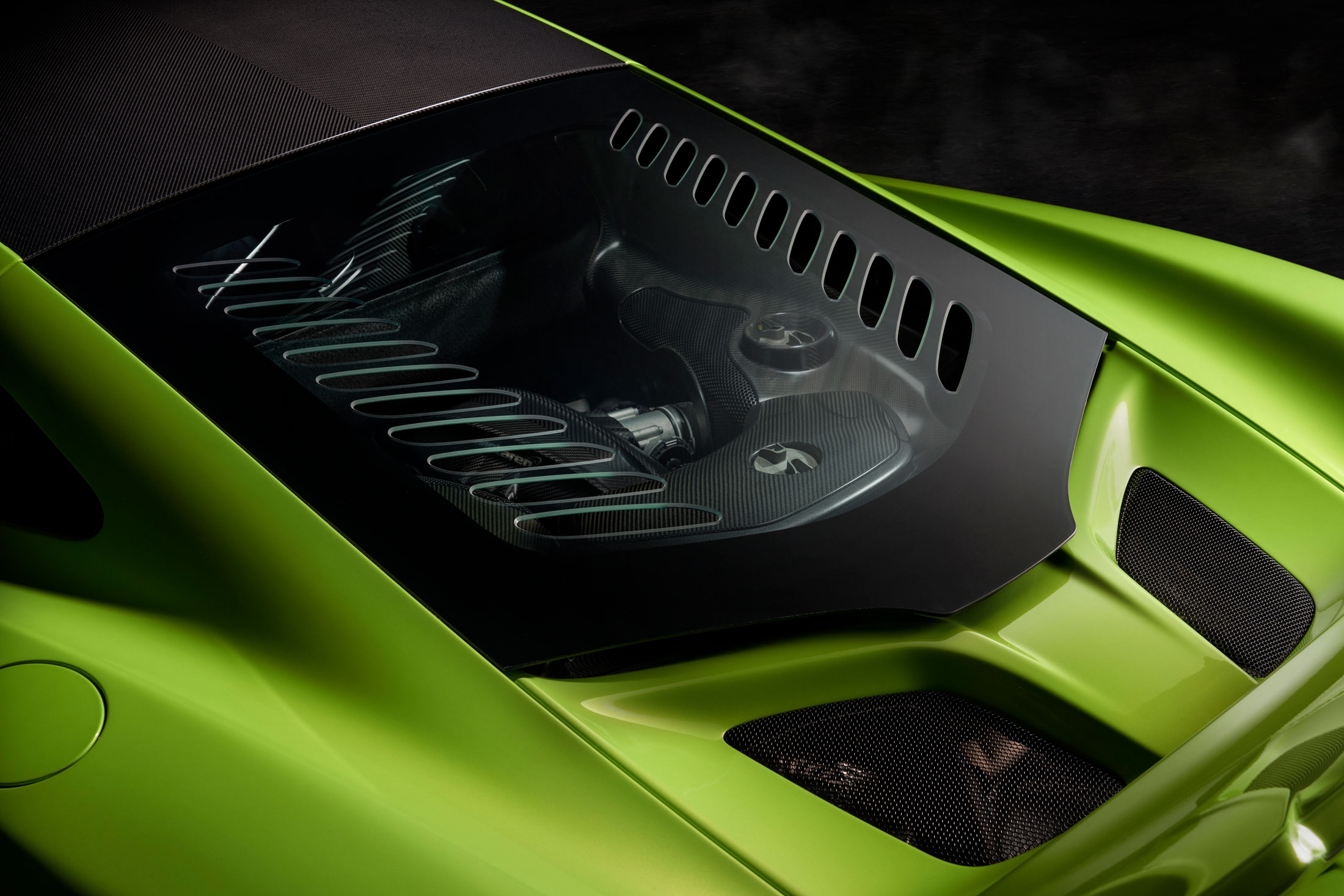 McLaren 675LT engine bay with carbon fiber detailing, visible through lightweight glass cover, showcasing engineering