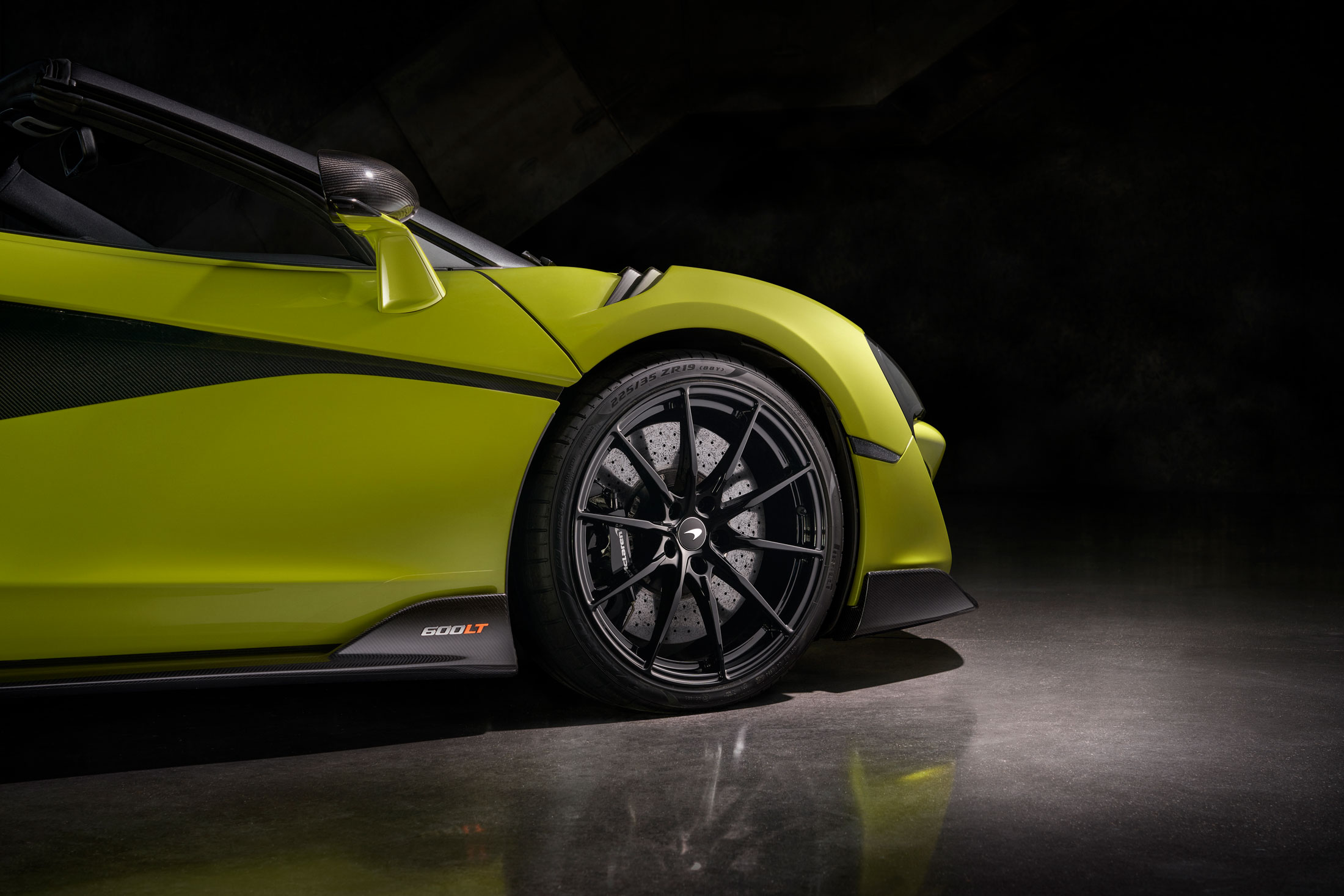 The front side of McLaren 600LT in vibrant green with carbon fiber aero, lightweight wheels, and high-performance braking system