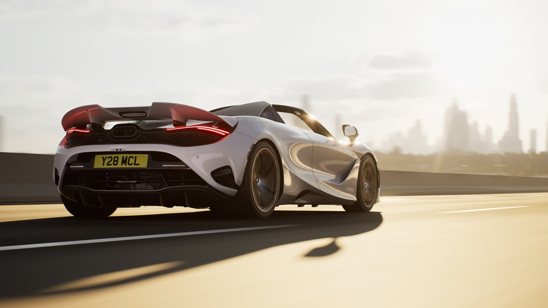 Rear view of a white McLaren 750S Spider driving at speed in the sun, towards a city.