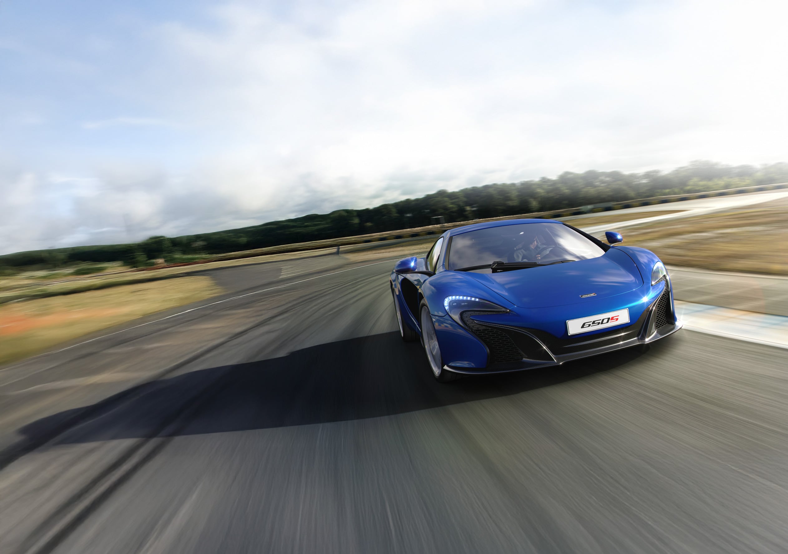 Blue McLaren 650S driving around a winding track at speed.