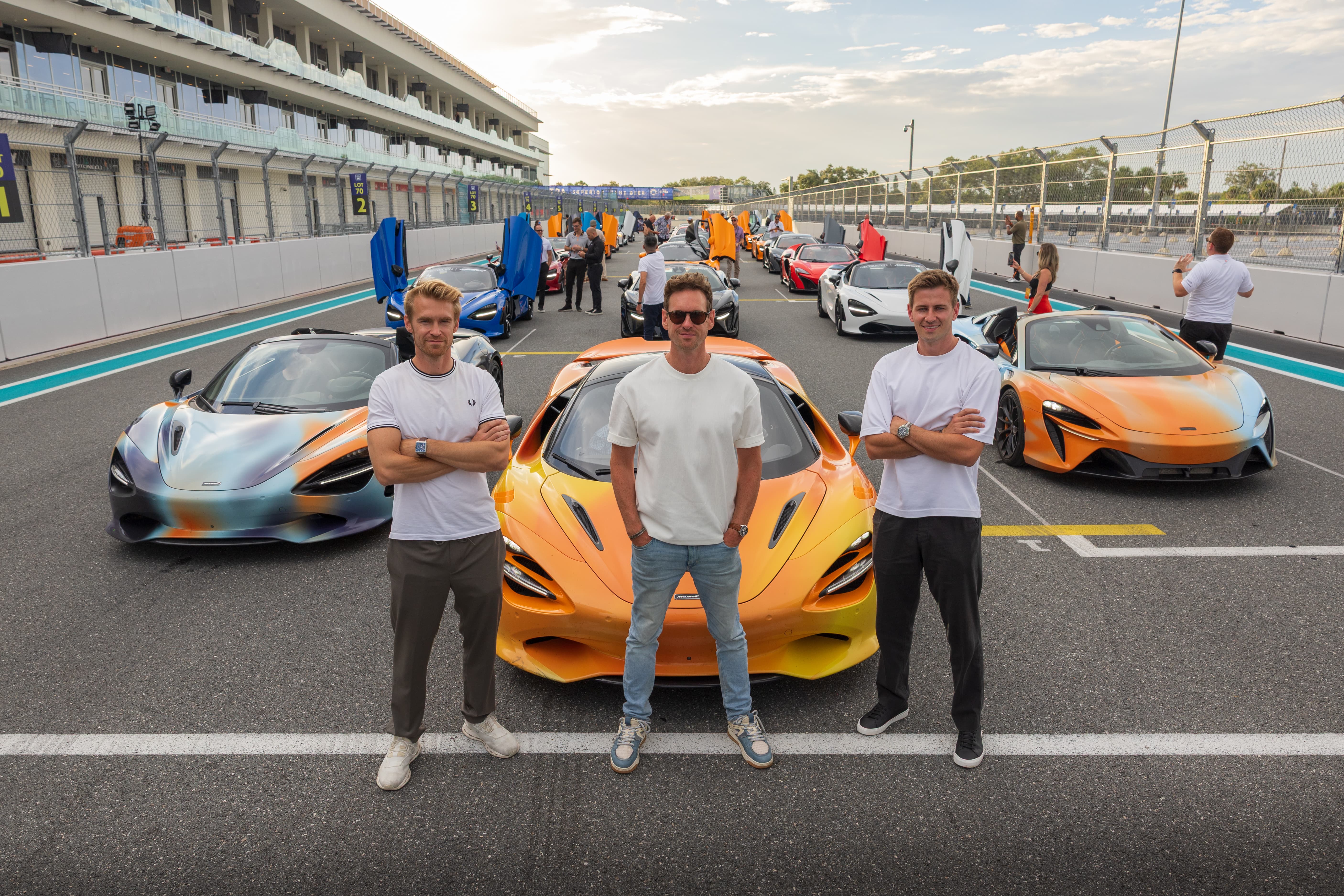 The McLaren States of Endurance team posing with their cars, parked on the finishing line of the Miami International Autodrome. The customer convoy parked down the track behind them. A scene from Day 11 of the 'McLaren States of Endurance' road trip.