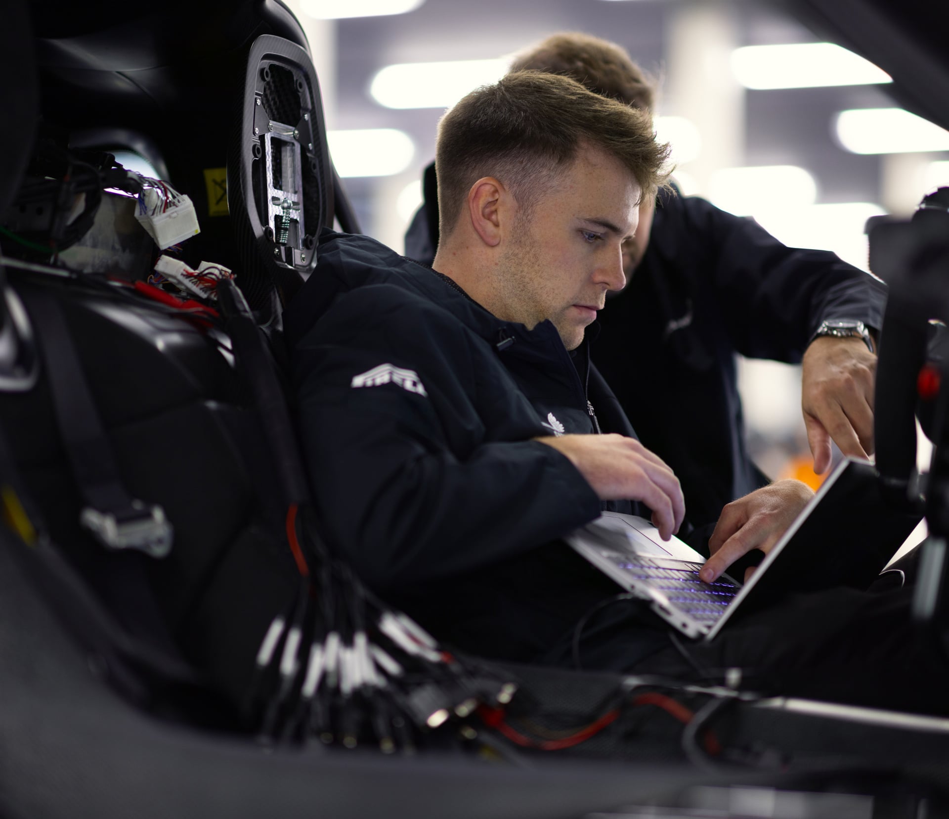 A McLaren engineer sat in the drivers seat of the McLaren W1 with their laptop open.