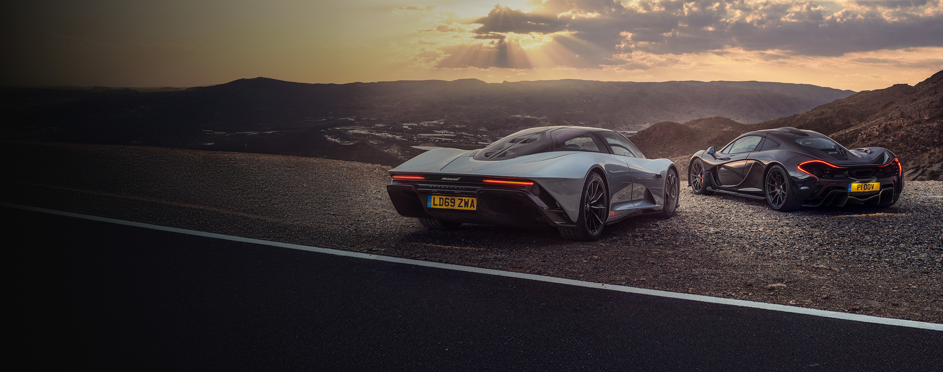 The McLaren Speedtail and P1 parked overlooking a sunset across open valley.