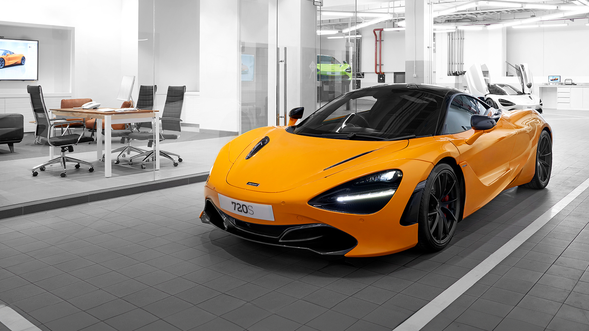 McLaren Jakarta official retailer showroom interior. A McLaren 720S supercar in vibrant McLaren Orange is parked on the service bay floor, with a meeting/consultation area visible in the background.