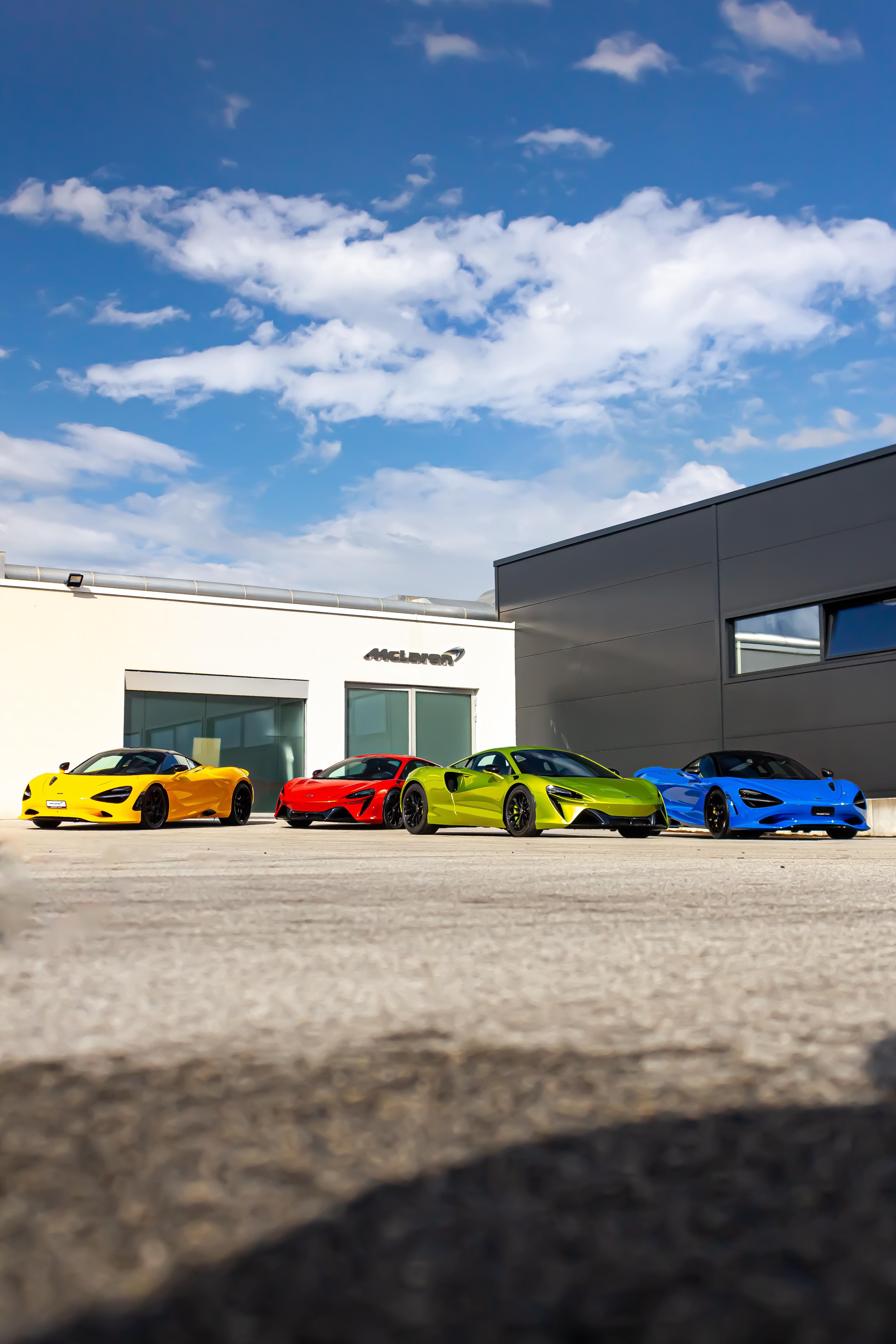 A bright, colourful range of McLaren cars parked outside the McLaren Geneva storefront.