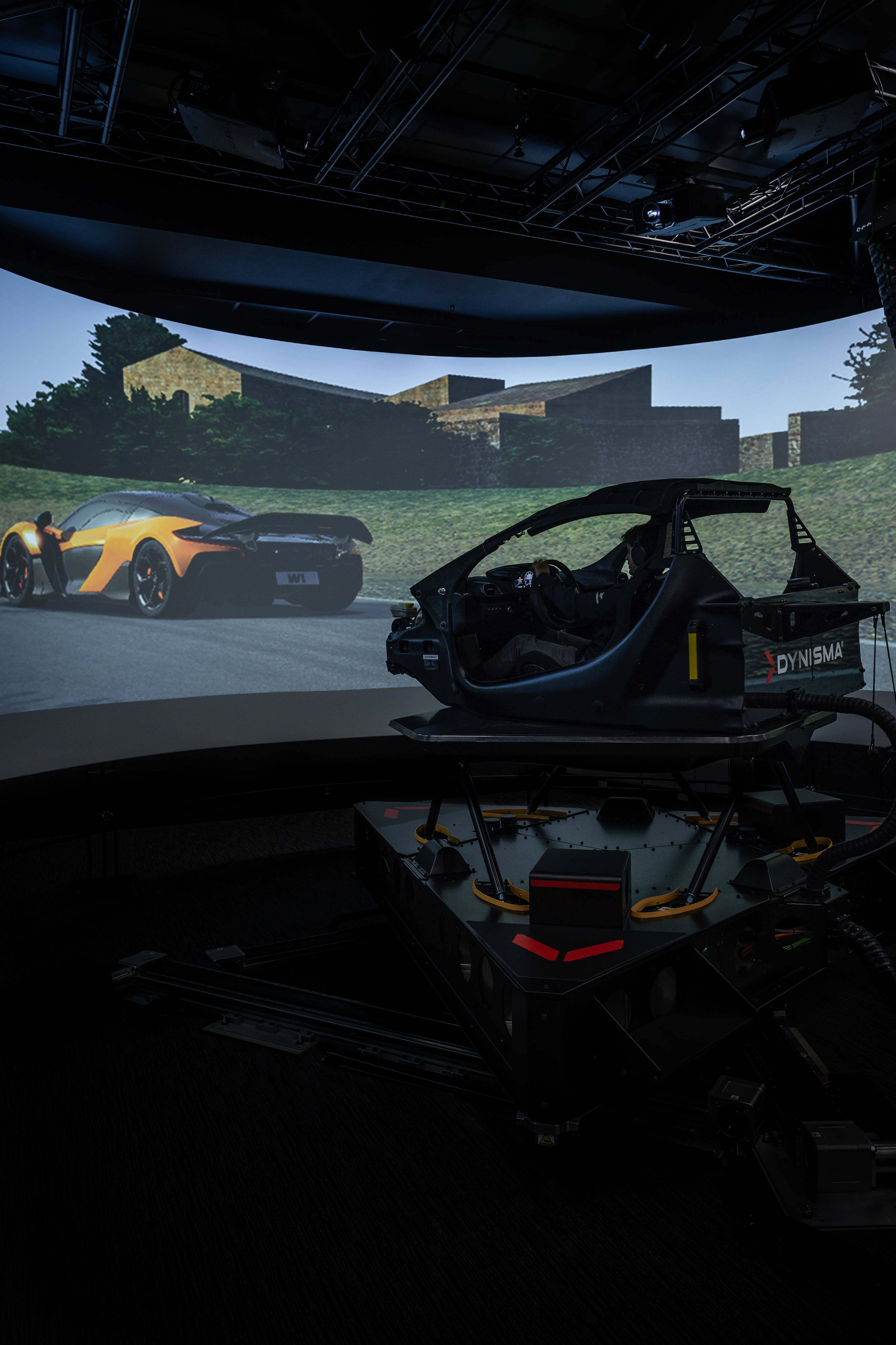 McLaren driver testing in a high-fidelity Dynisma motion simulator, highlighting the advanced technology partnership for dynamic vehicle development.