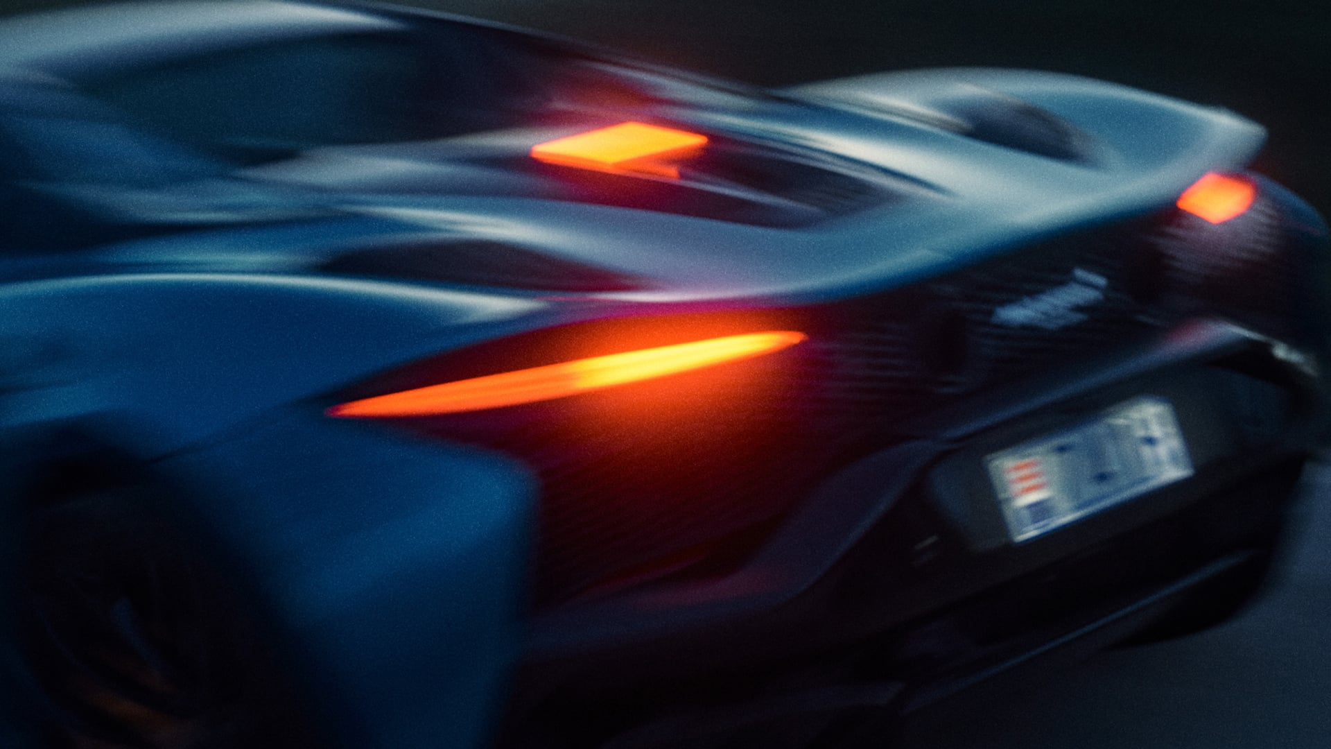 A dynamic shot of the rear of a McLaren Artura Spider driving at speed.