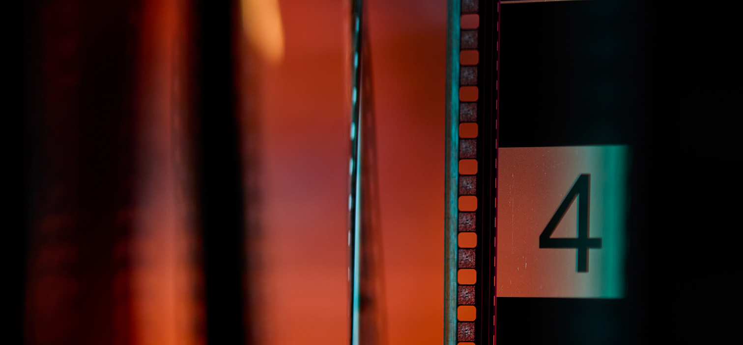 Film strip with glowing orange and teal tones, featuring a visible frame labeled “4” along the edge.